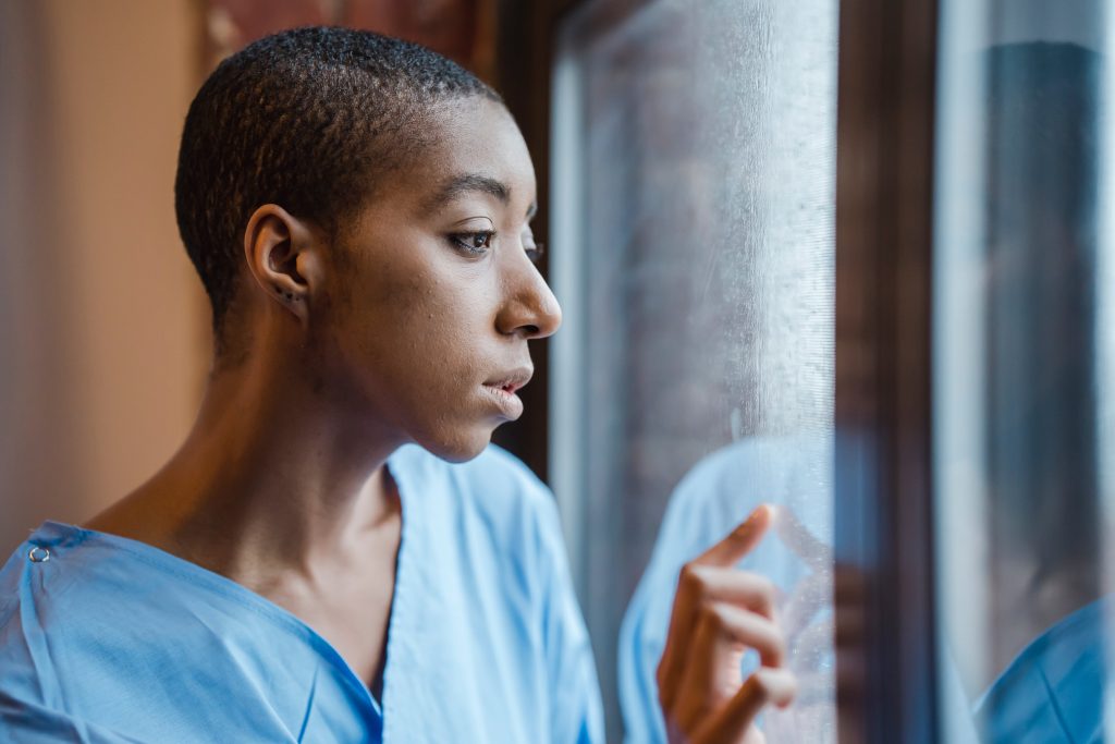 Melancholic black woman looking at window in clinic